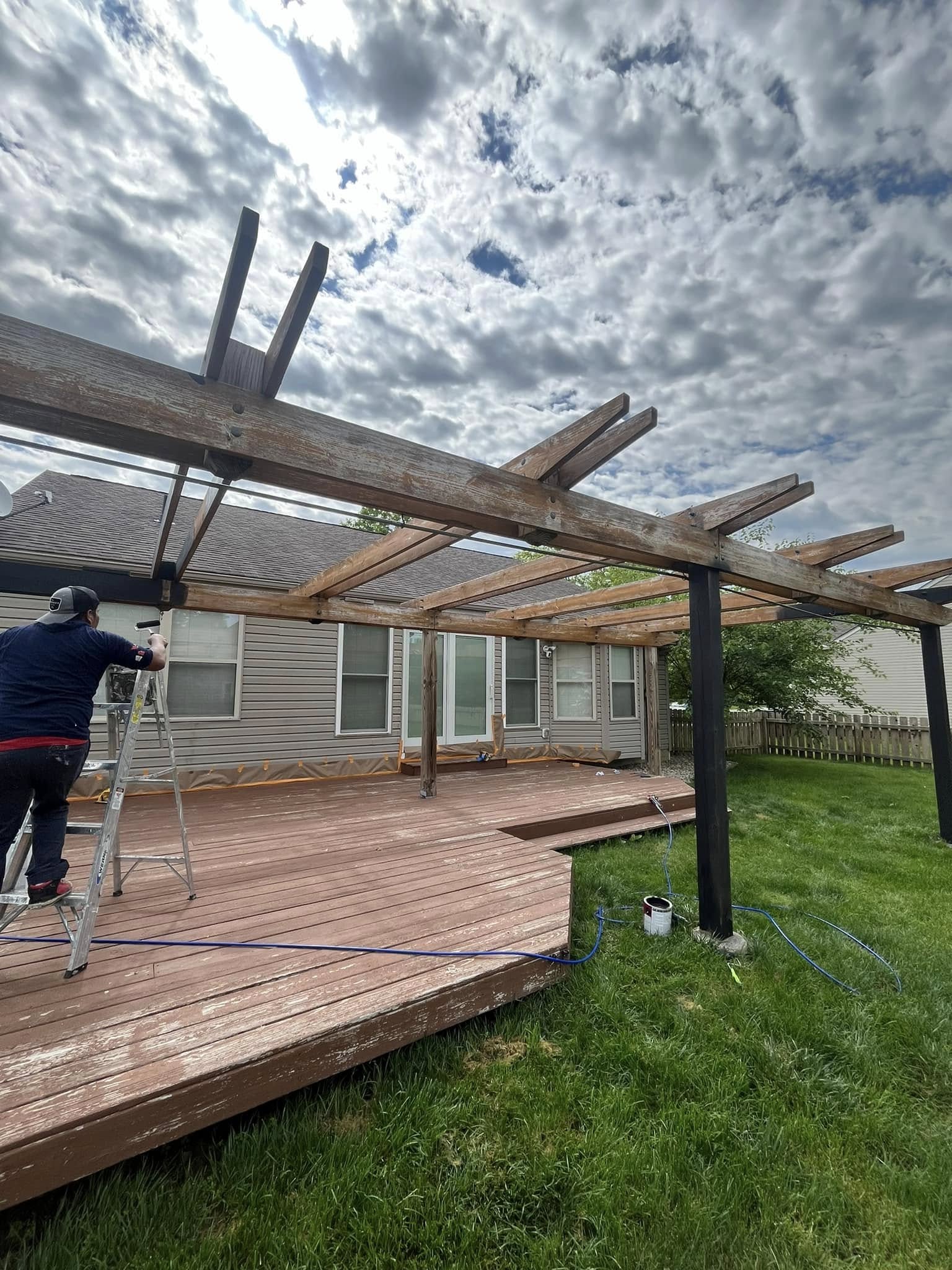614 Painting crew member staining a pergola from a ladder