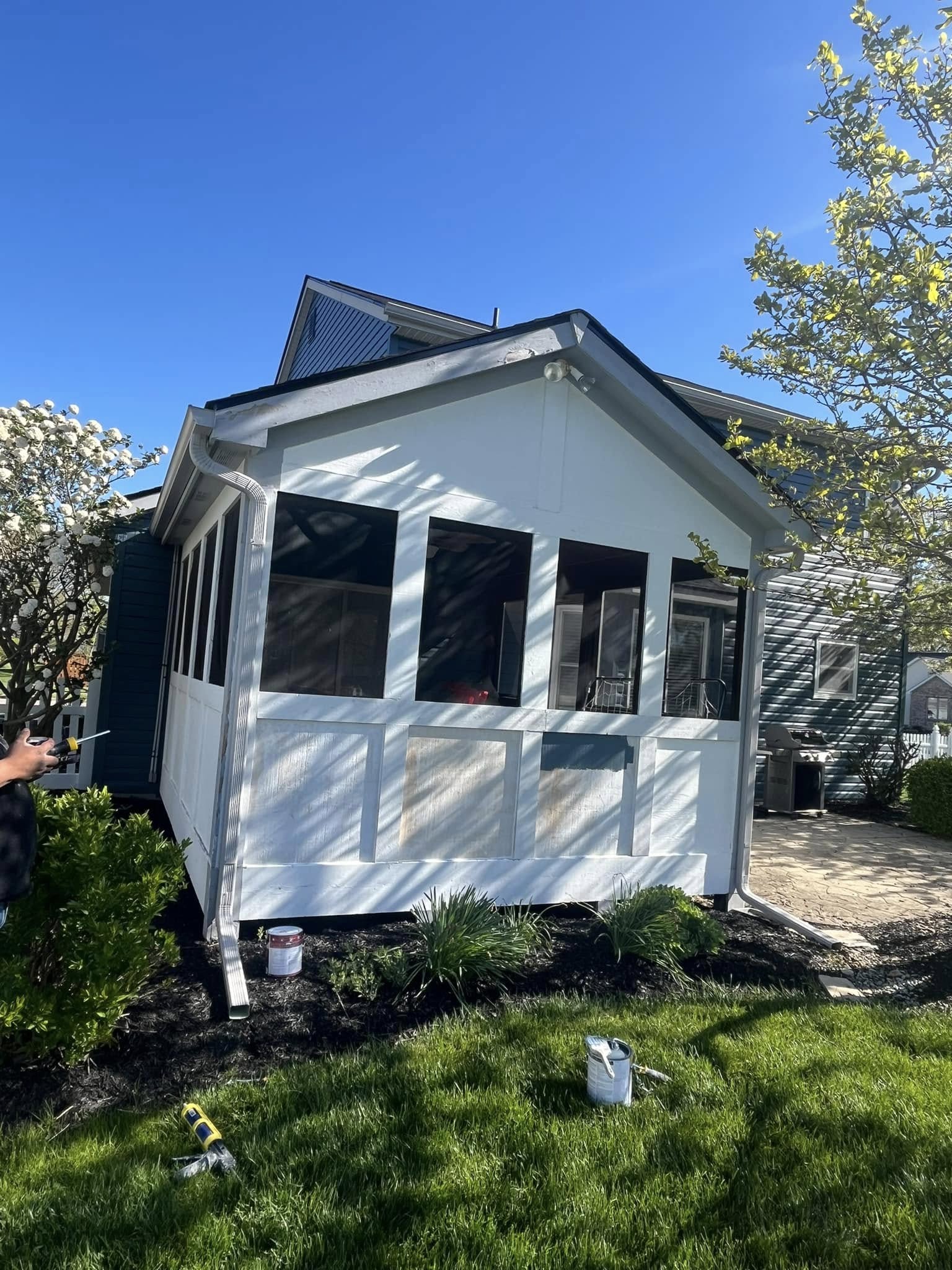 Screened porch mid-repaint with white primer and paint cans